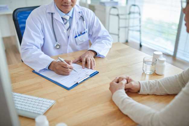 Doctor filling out paper form with patient
