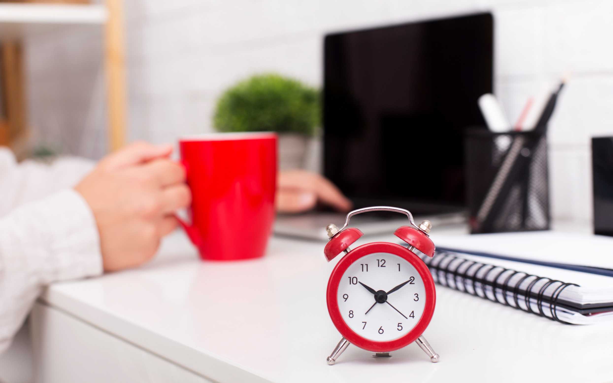 Red alarm clock in the foreground on top of a desk